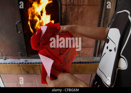 Students burning paper money Chinese New Year celebrations in the temple pagoda in Sibu, Borneo, Malaysia Stock Photo