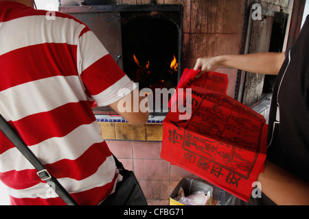 Students burning paper money during Chinese New Year celebrations in the temple pagoda in Sibu, Borneo, Malaysia Stock Photo