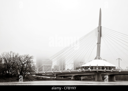 Esplanade Riel Bridge crossing the Red River on a foggy fall morning. Skyline of Winnipeg, Manitoba, Canada in the background. Stock Photo