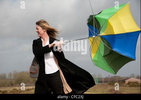 Woman holding onto her umbrella which has blown inside out in a high wind Stock Photo