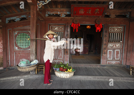 Woman with baskets passing Chua Cau, Japanese Bridge, Hoi An, Annam, Vietnam Stock Photo