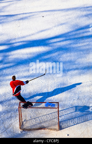 Teenage boy playing ice hockey on the frozen Assiniboine River. The Forks, Winnipeg, Manitoba, Canada.