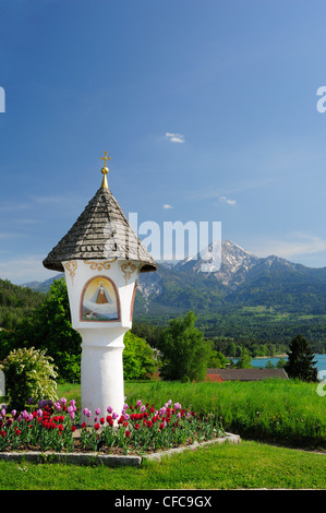 Shrine decorated with flowers in front of lake Faaker See and Mittagskogel, Karawanken range, lake Faaker See, Carinthia, Austri Stock Photo