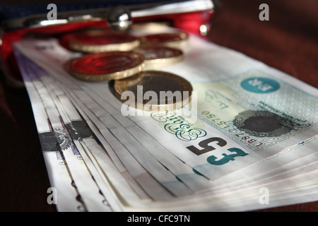 Sterling notes and coins poking out of an open lady's purse Stock Photo