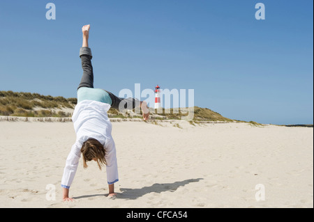 Woman turning cartwheels on sandy beach, Ellenbogen, List, Sylt, Schleswig-Holstein, Germany Stock Photo