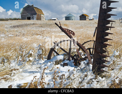 old barn with sickle bar hay mower in the foreground near Hazenmore, Saskatchewan, Canada Stock Photo