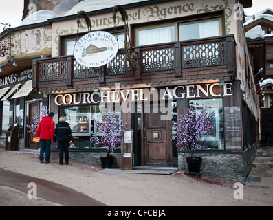 Two people looking in a window of an estate agents office at Courchevel 1850 Three Valleys France Stock Photo