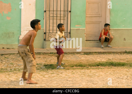 A group of teenage boys playing a game of baseball in the streets of Trinidad Cuba Stock Photo