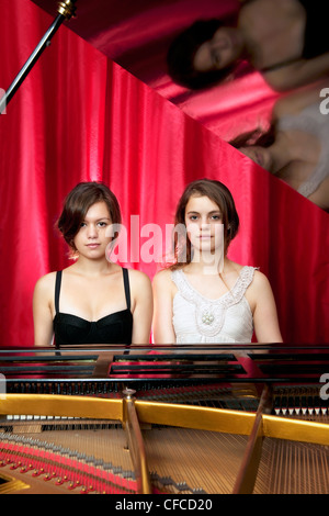 Two young woman playing together on a grand piano (quatre mains) Stock Photo