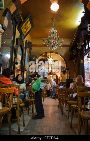 Local man tries to sell his wares to customers in a cafe in Cairo Stock Photo