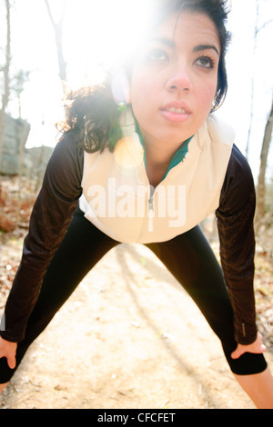 Athletic female stretches before a trail run in the woods during winter. Stock Photo