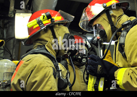 Sailors in a damage control repair party make their way into a space ...