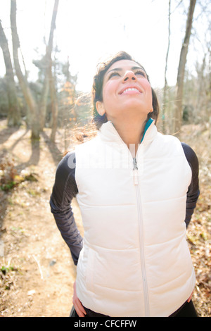 Athletic female stretches before a trail run in the woods during winter. Stock Photo