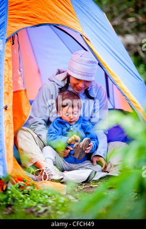 a mother and son sit in a blue and orange tent, and put their shoes on, at their campsite which is at approximately 10,120 feet Stock Photo