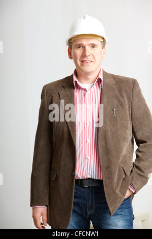 Cheerful architect standing. Wearing hardhat. Stock Photo