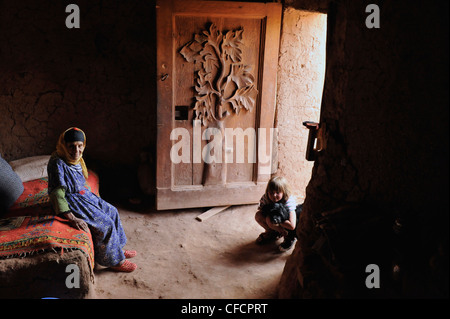 Old Berber woman and young European girl in traditional Berber house with adorned door, Kasbah Ait Benhaddou, Ait Benhaddou, Atl Stock Photo