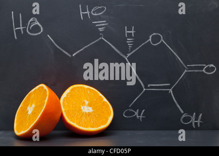 Structural formula of vitamin C on blackboard with orange Stock Photo