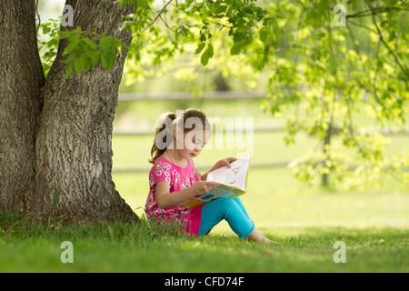 Girl sitting under a tree reading a book in Green Park London Stock ...