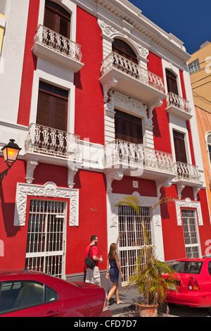 OLD SAN JUAN, PUERTO RICO - Couple walks by historic building with balconies on Calle de Tetuan. Stock Photo