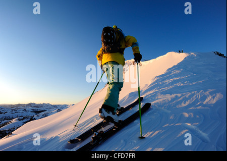 A skier skinning up a snow covered slope at sunrise in the Sierra Nevada near Lake Tahoe, California. Stock Photo