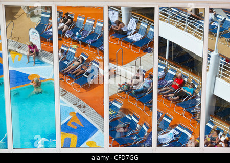 Pool area reflected on large panes of glass aboard Royal Caribbean's Allure of the Seas cruise ship. Stock Photo