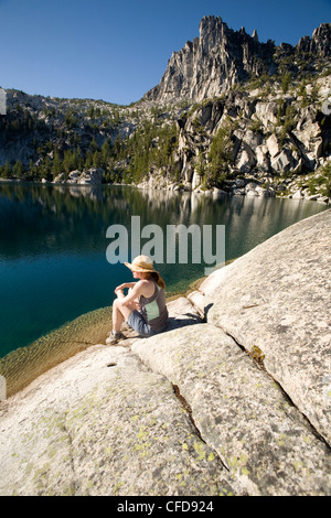 Woman sitting on the shore of Lake Viviane, Enchantment lakes, Alpine Lakes Wilderness, Levenworth, Washington State, USA Stock Photo