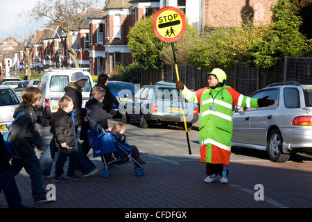 Lollipop lady helping school children cross road Stock Photo