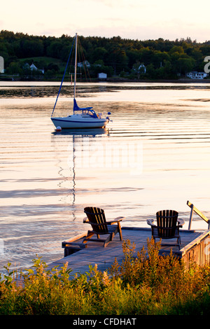 Lawn chairs on wharf and sailboat in sunset, LaHave River, Nova Scotia, Canada2 Stock Photo
