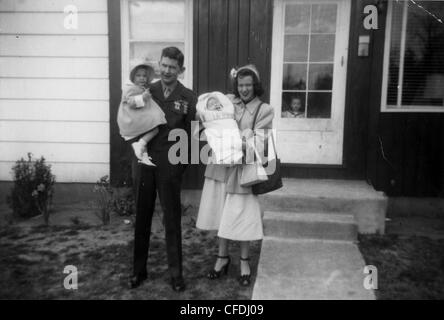 marine standing on porch with wife and kids during WWII military family 1940s babyboomers Stock Photo