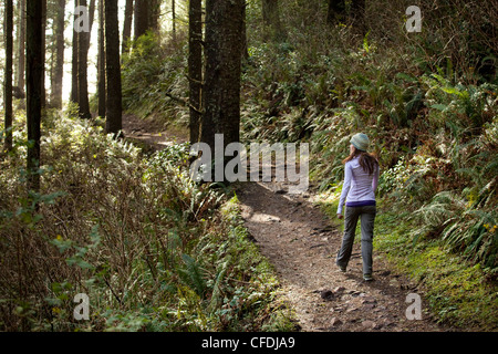 Female walking on trail through woods. Stock Photo
