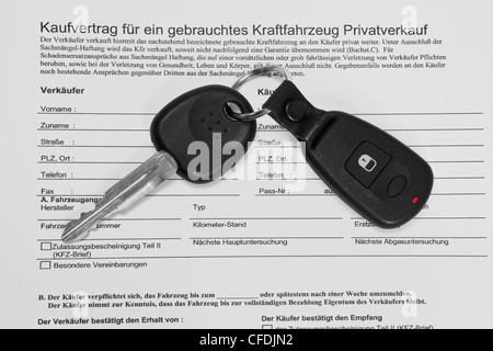 Detail photo of a Car sales agreement in German language, alongside is car key. Stock Photo