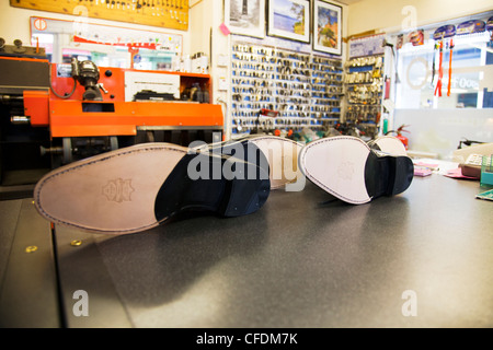 New leather soles & heels on shoes on display in shoe repair shop cobblers workshop Stock Photo