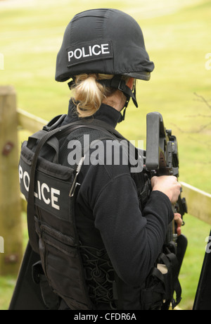 A female police firearms officer armed with an Heckler and Koch G36C assault rifle observes an incident. Real Police SWAT. Stock Photo