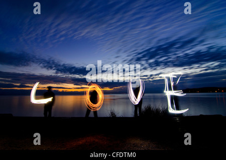 Family uses flashlights paint word love along Stock Photo