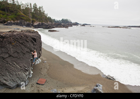 A man bouldering along the coast of Ucluelet, BC near Pacific Rim National Park, British Columbia, Canada Stock Photo