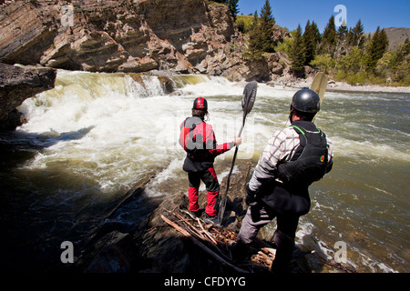 Two male whitewater kayakers scout the falls on the Oldman River, Alberta, Canada Stock Photo