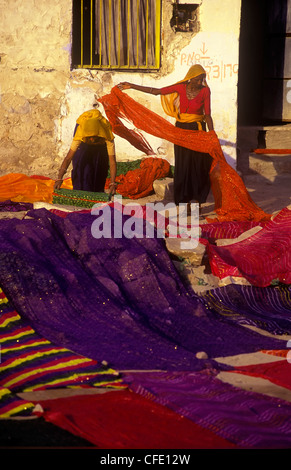 Indian women at a fabric warehouse lay out colourful fabrics to dry in Delhi, India Stock Photo