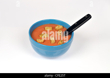 A bowl of tomato soup with croutons and a spoon on white background cut out. Stock Photo