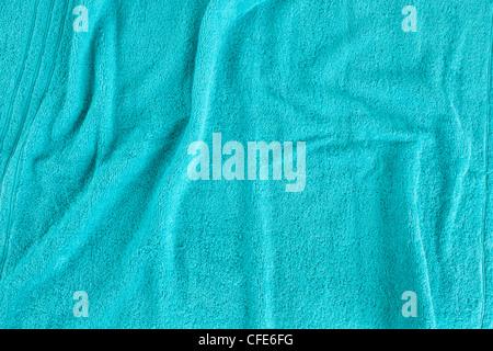Looking down on an unfolded spread out towel that is slightly ruffled. Blue background image of towelling texture Stock Photo