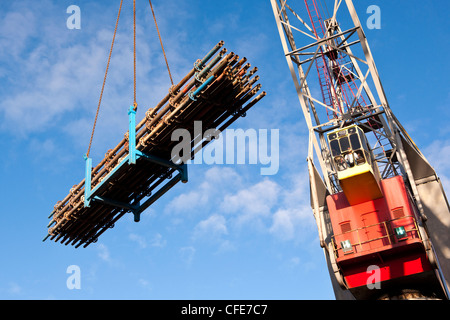 Heavy duty crane lifting a rig with scaffolding materials on a construction yard Stock Photo