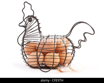 Brown hen's eggs in a black wire storage basket shaped like a hen with two hen's feathers on a white background Stock Photo