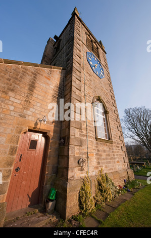 External doorway entrance (wooden door closed) at base of church belfry tower with blue clock - St Peter's Church, Addingham, West Yorkshire, GB, UK. Stock Photo