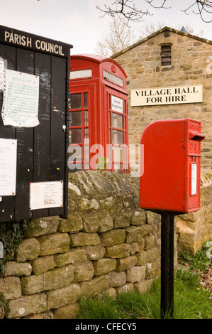 Street furniture - parish noticeboard, red post box & iconic K6 telephone box by village hall (for hire sign) - Leathley, North Yorkshire, England, UK Stock Photo