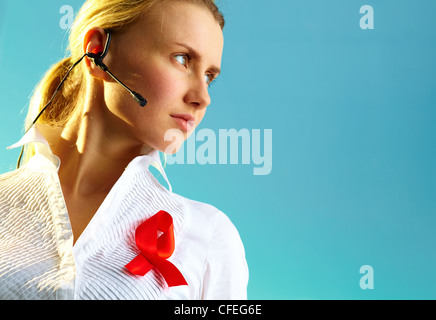 Portrait of pretty woman with headset and red ribbon on blouse over blue background Stock Photo