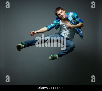 Guy with a wide smile jumping sideward and looking at camera Stock Photo