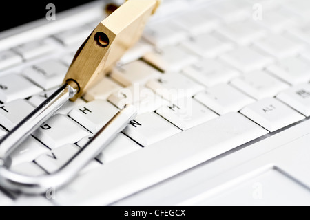 Brass padlock in unlocked position on top of computer keyboard Stock Photo