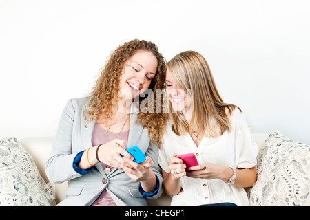 Two smiling women using mobile devices with colorful cases Stock Photo