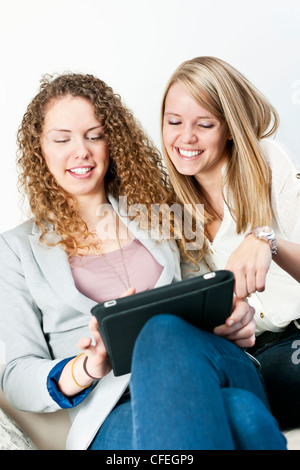 Two young smiling women using tablet computer at home Stock Photo