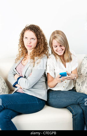 Young woman ignoring her friend checking smart phone breaching cellphone etiquette Stock Photo