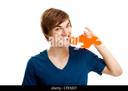 Young man holding and biting a puzzle piece, isolated on white background Stock Photo